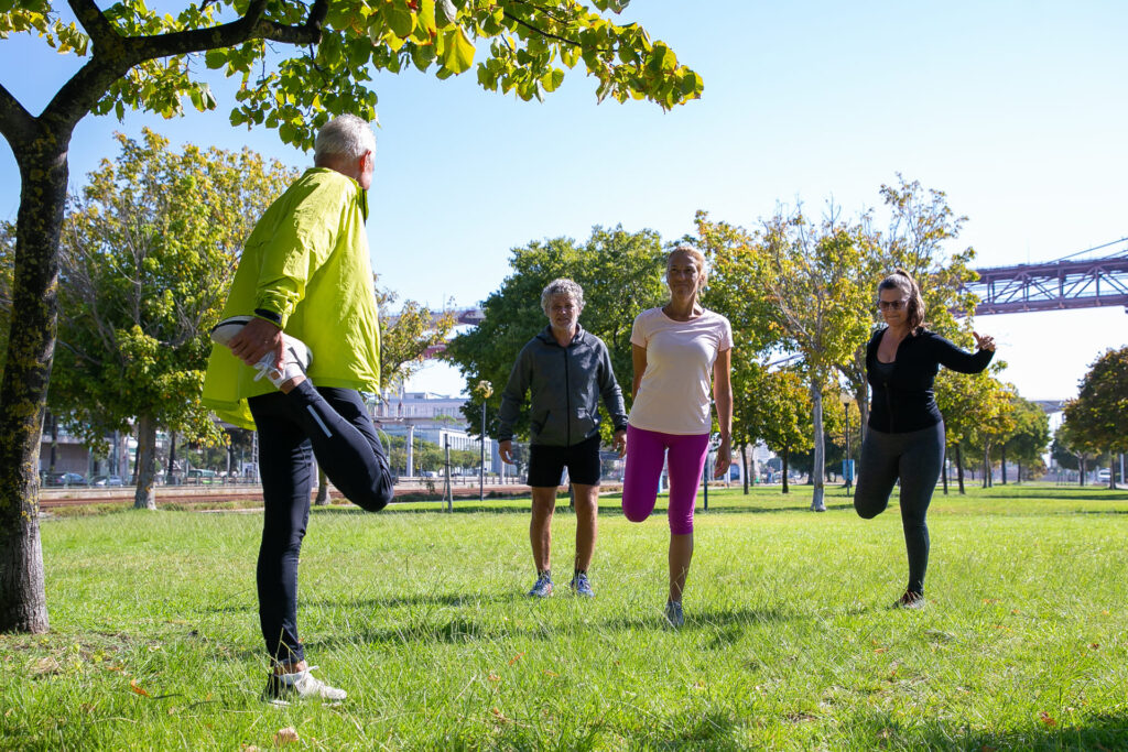 Un groupe d'adultes effectuant des exercices d'étirement en plein air dans un parc, promouvant une activité physique régulière pour la santé.