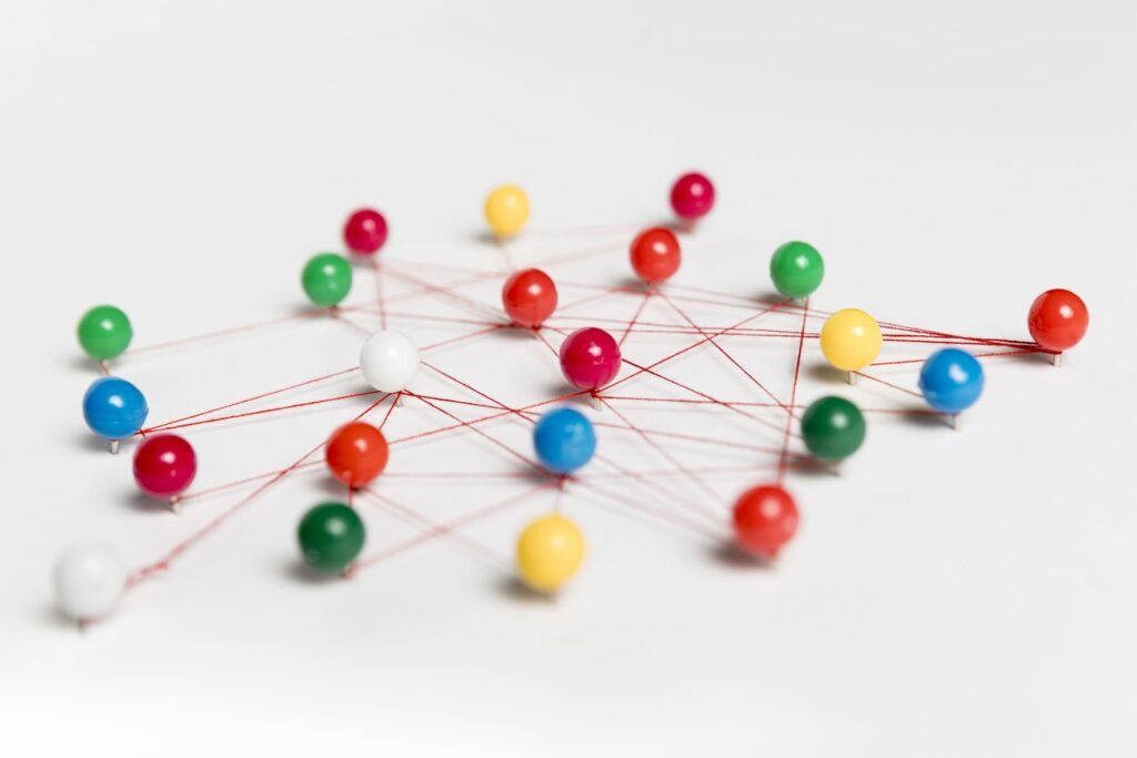 Réseau de connexions colorées symbolisant le mind mapping, avec des épingles reliées par des fils rouges.