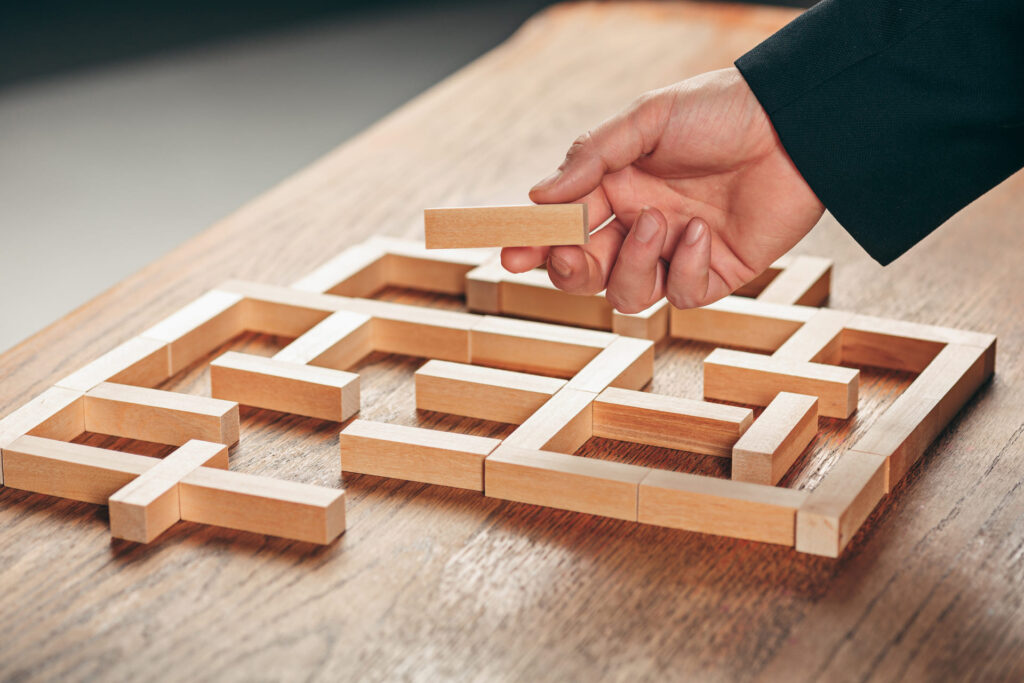Une place principale une pièce en bois dans un labyrinthe construit avec des blocs de bois, symbolisant la construction de schémas de pensée et d'organisation.