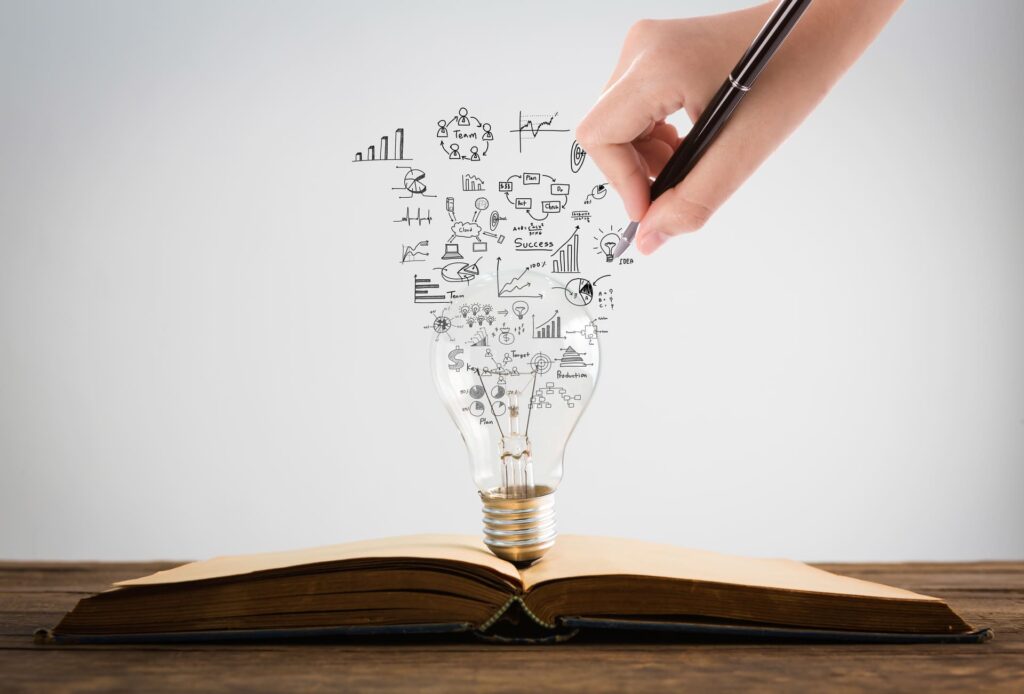 Une principale dessine des symboles et des schémas sortant d'une ampoule posée sur un livre ouvert, représentant la créativité et l'acquisition de connaissances.
