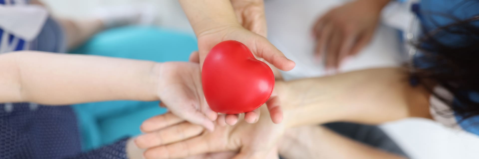 Des mains se transmettant un cœur rouge en symbole de soin et de solidarité.